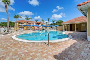 A swimming pool with lounge chairs, palm trees, and a building with a red roof. - Townhome in Berkeley Lake Resort, 9 Mi to Wdw! (Kissimmee)