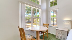 A room with a round table, two chairs, a dresser, and large windows with a view of the outside. - Townhome in Berkeley Lake Resort, 9 Mi to Wdw! (Kissimmee)