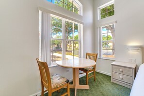 A room with a round table, two chairs, a dresser, and large windows with a view of the outside. - Townhome in Berkeley Lake Resort, 9 Mi to Wdw! (Kissimmee)