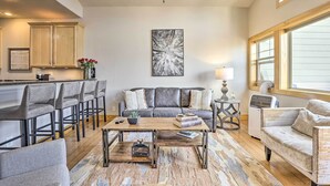 Ein geräumiges Wohnzimmer mit grauem Sofa, Couchtisch und Barbereich mit Hockern.