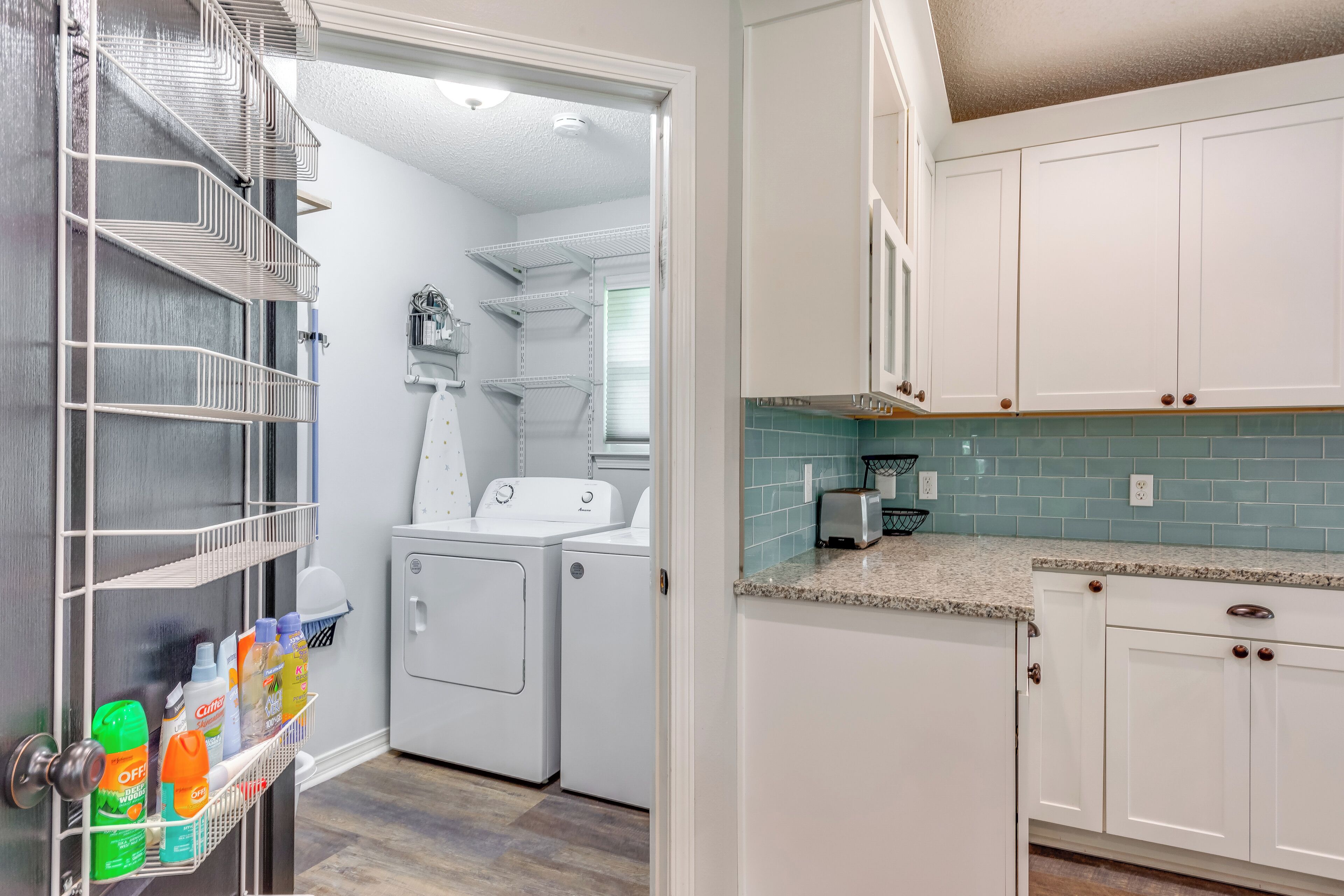A laundry area with a metal rack holding detergent bottles, a washing machine, and a dryer.