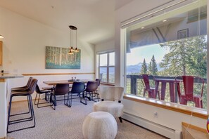 A modern dining area with a large window overlooking a deck with red chairs. - 10 Mi to Keystone Slopes: Mtn-view Condo! (Silverthorne)