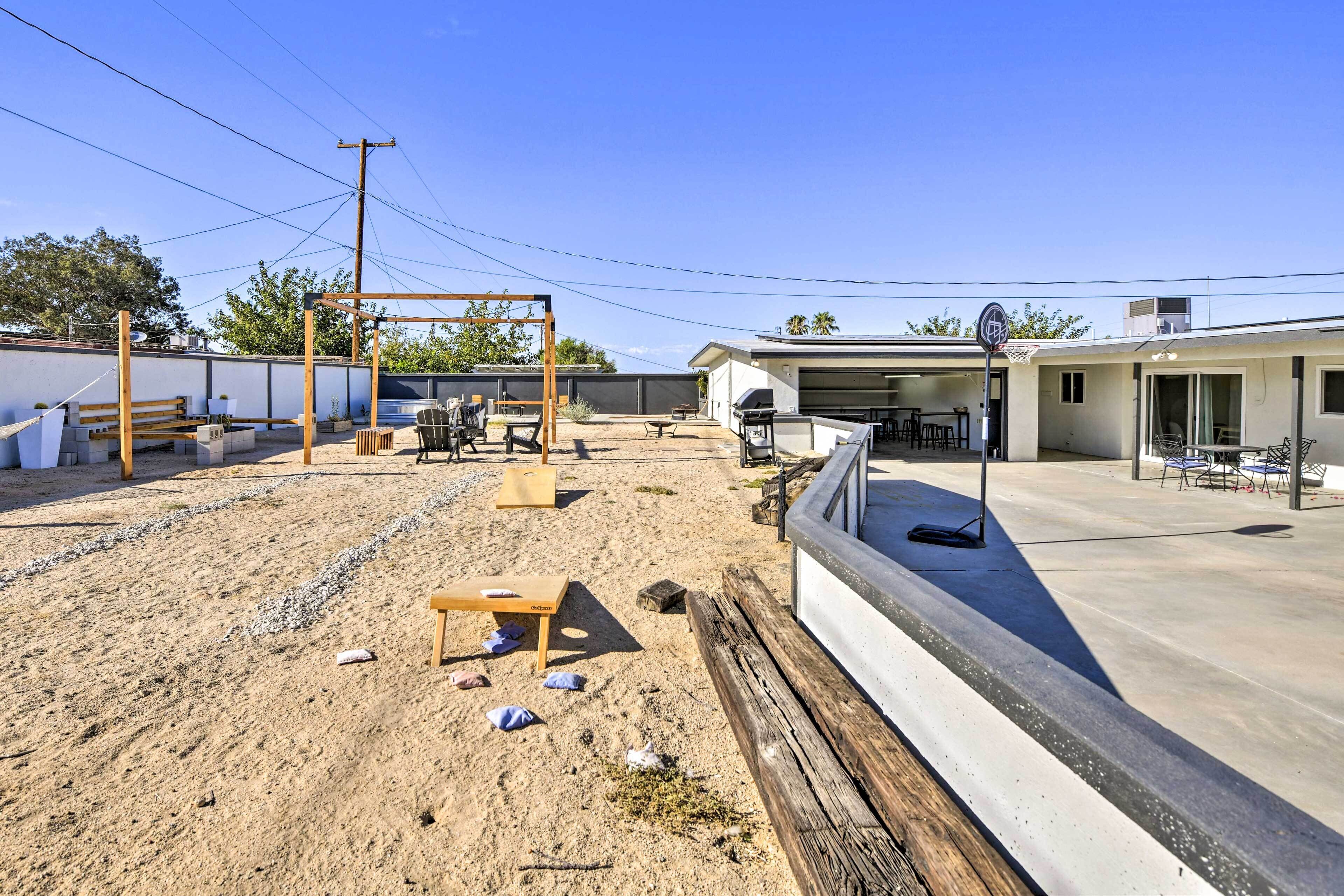 A residential backyard with a wooden swing set, a barbecue grill, and a concrete patio.