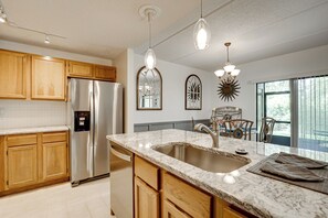 A modern kitchen with wooden cabinets, stainless steel appliances, a granite countertop, and pendant lighting. - St Augustine Condo w/ Screened Porch, Pool Access! (St. Augustine)