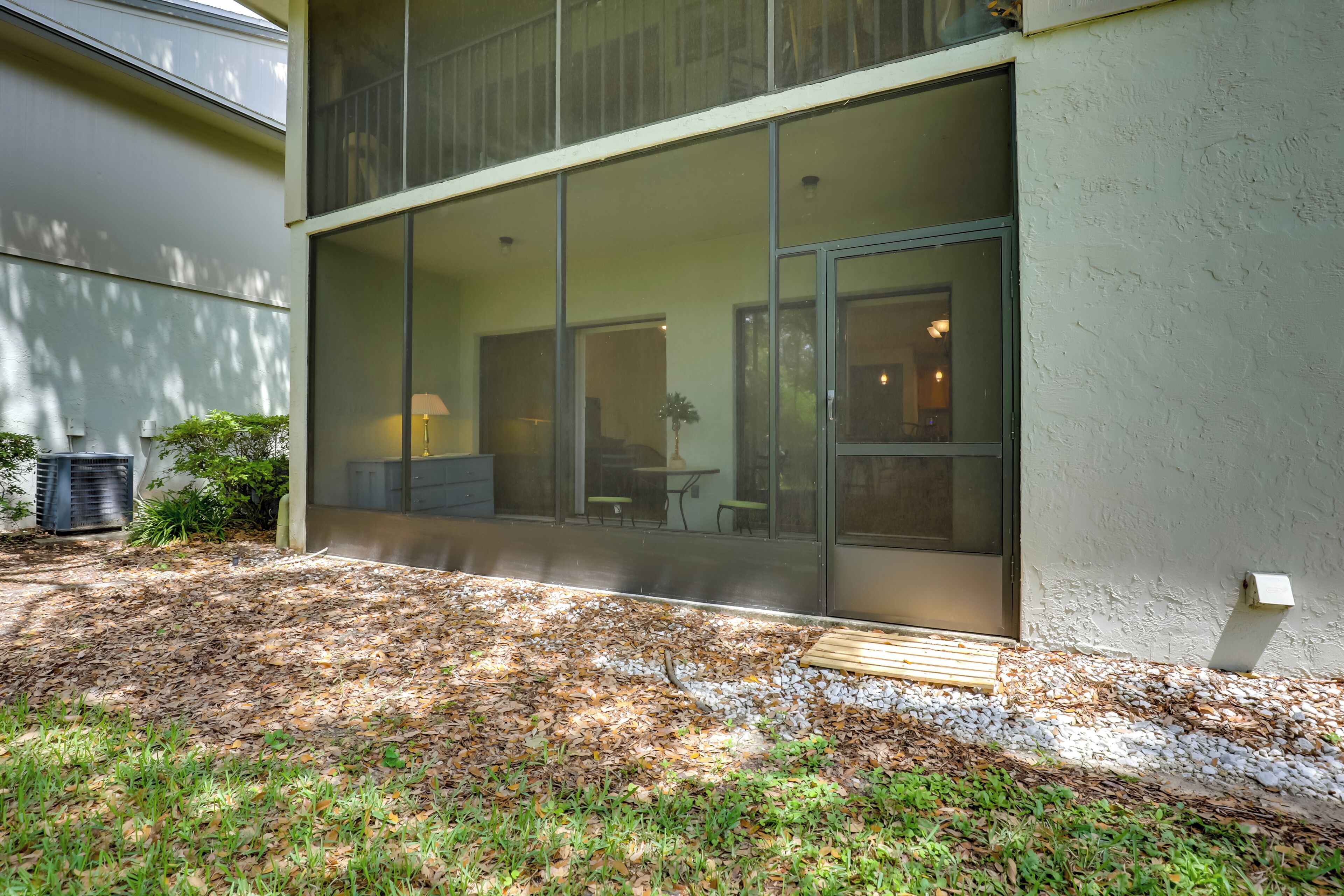 A modern building with large glass windows, a grassy area with mulch, and a small wooden deck.
