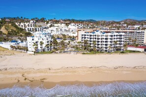 Una località balneare con diversi edifici bianchi, una spiaggia sabbiosa e palme.