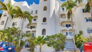 A white building with balconies and palm trees, labeled "Villa Astori." - Beachfront Oasis in Cabo w/ Resort Amenities! (San José del Cabo)
