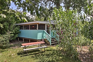 A rustic cabin with a covered porch, a picnic table, and a staircase leading to a deck. - Cozy Middle Bass Cabin w/ Grill & Lagoon Access! (Put-in-Bay)