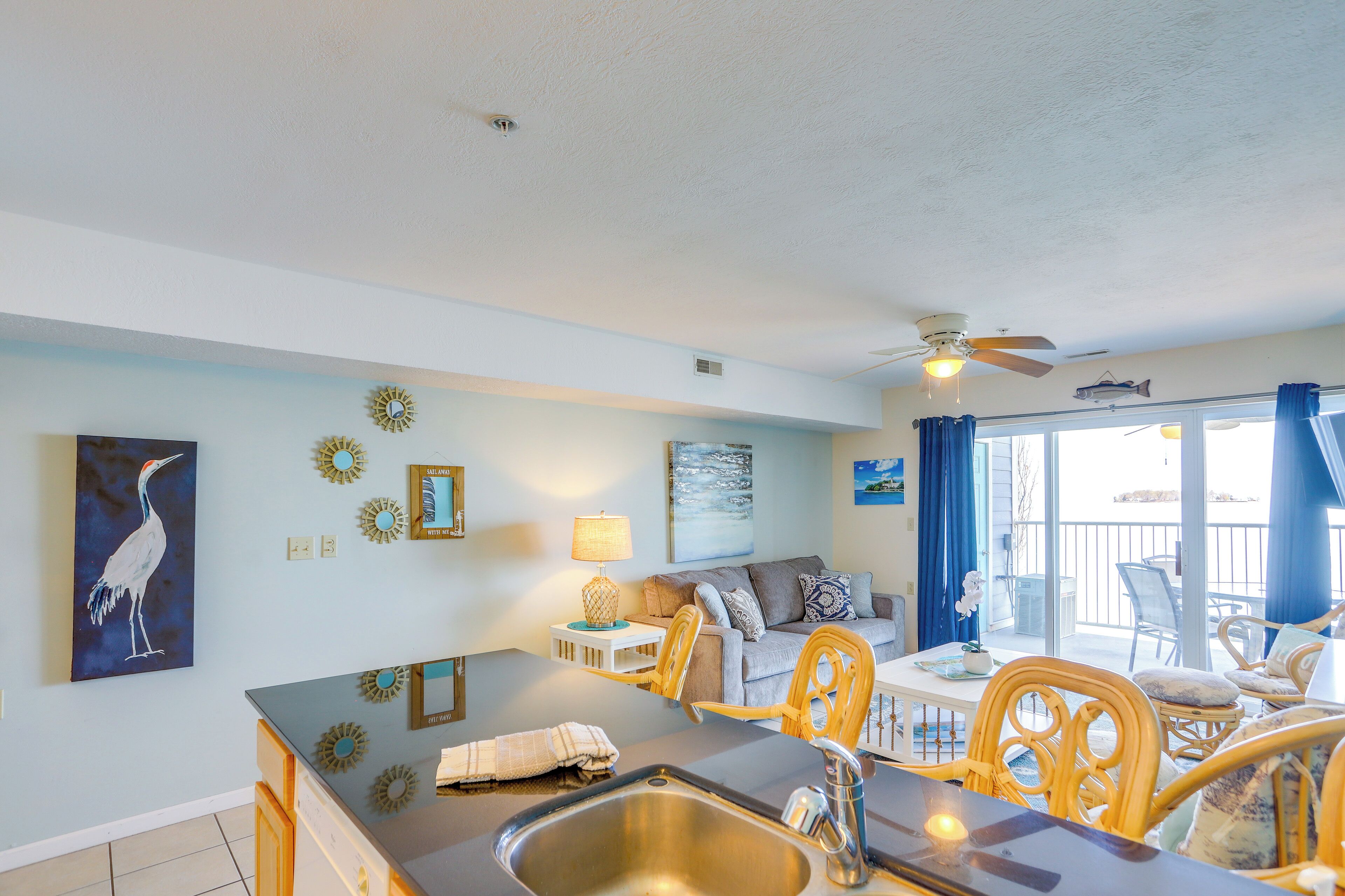 A well-lit kitchen with a sink, dining area with chairs, and a ceiling fan.