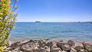 A clear view of a rocky shoreline with calm water and distant islands. - Waterfront Middle Bass Condo w/ Pool Access! (Put-in-Bay)
