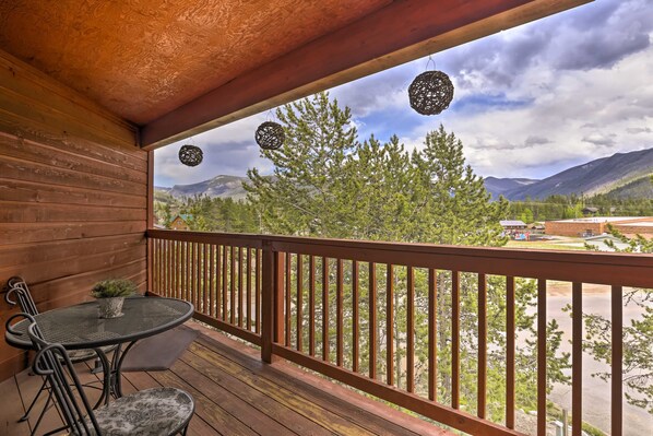 A wooden deck with a table and chairs, overlooking a mountainous landscape. - Steps to Grand Lake: Condo w/ Deck & Mtn Views (Grand Lake)
