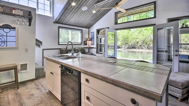 A modern kitchen with a large island, built-in appliances, and large windows offering views of the outdoors. - Floating Home on Columbia River w/ Provided Kayaks (Vancouver)