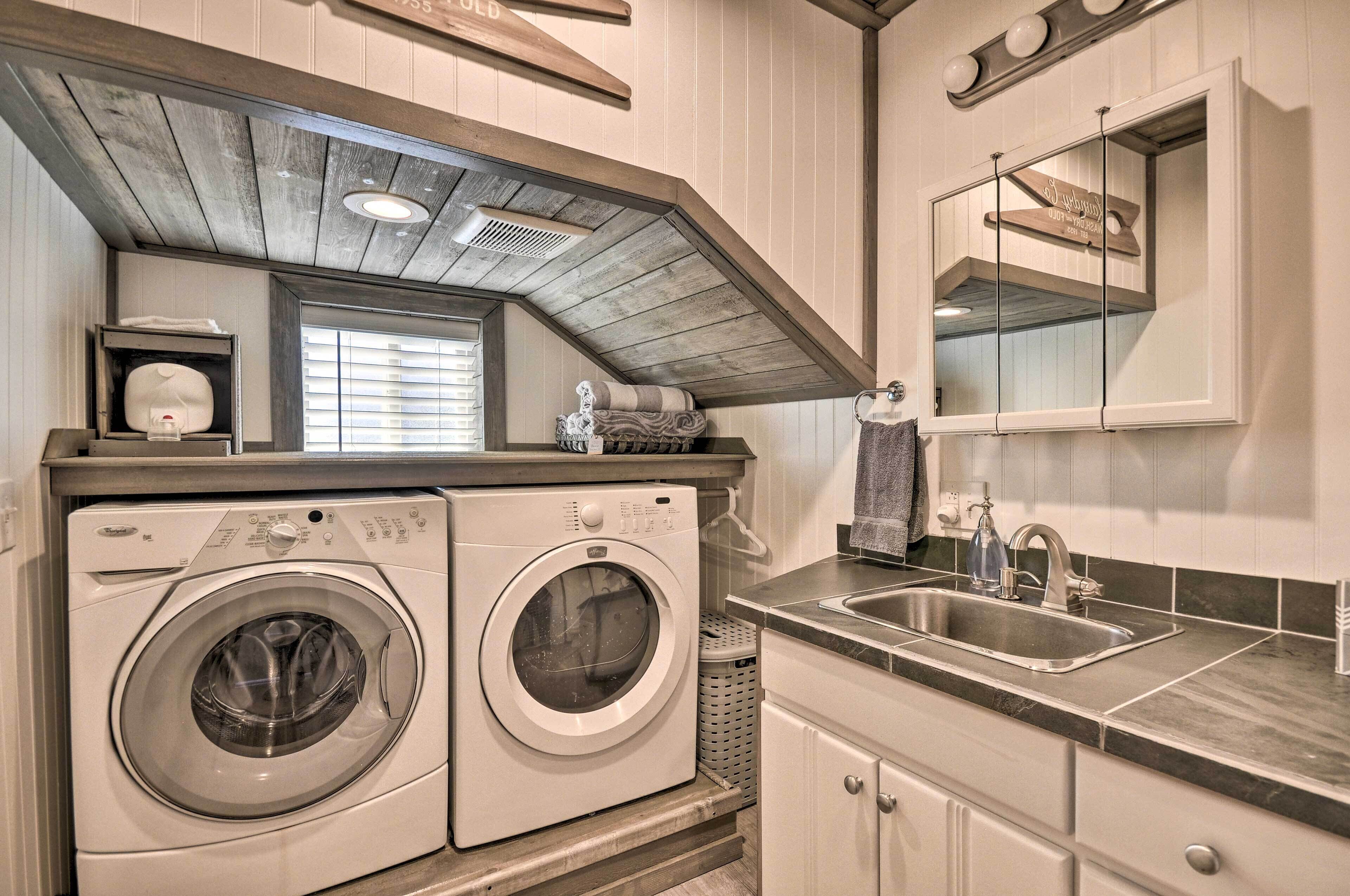 A laundry area with two washing machines, a sink, and a mirror above the sink.
