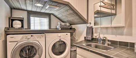 A laundry area with two washing machines, a sink, and a mirror above the sink.
