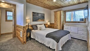 A bedroom with a wooden ceiling, a bed with a white and gray bedspread, a nightstand with a lamp, a dresser, and a window with blinds. - Floating Home on Columbia River w/ Provided Kayaks (Vancouver)