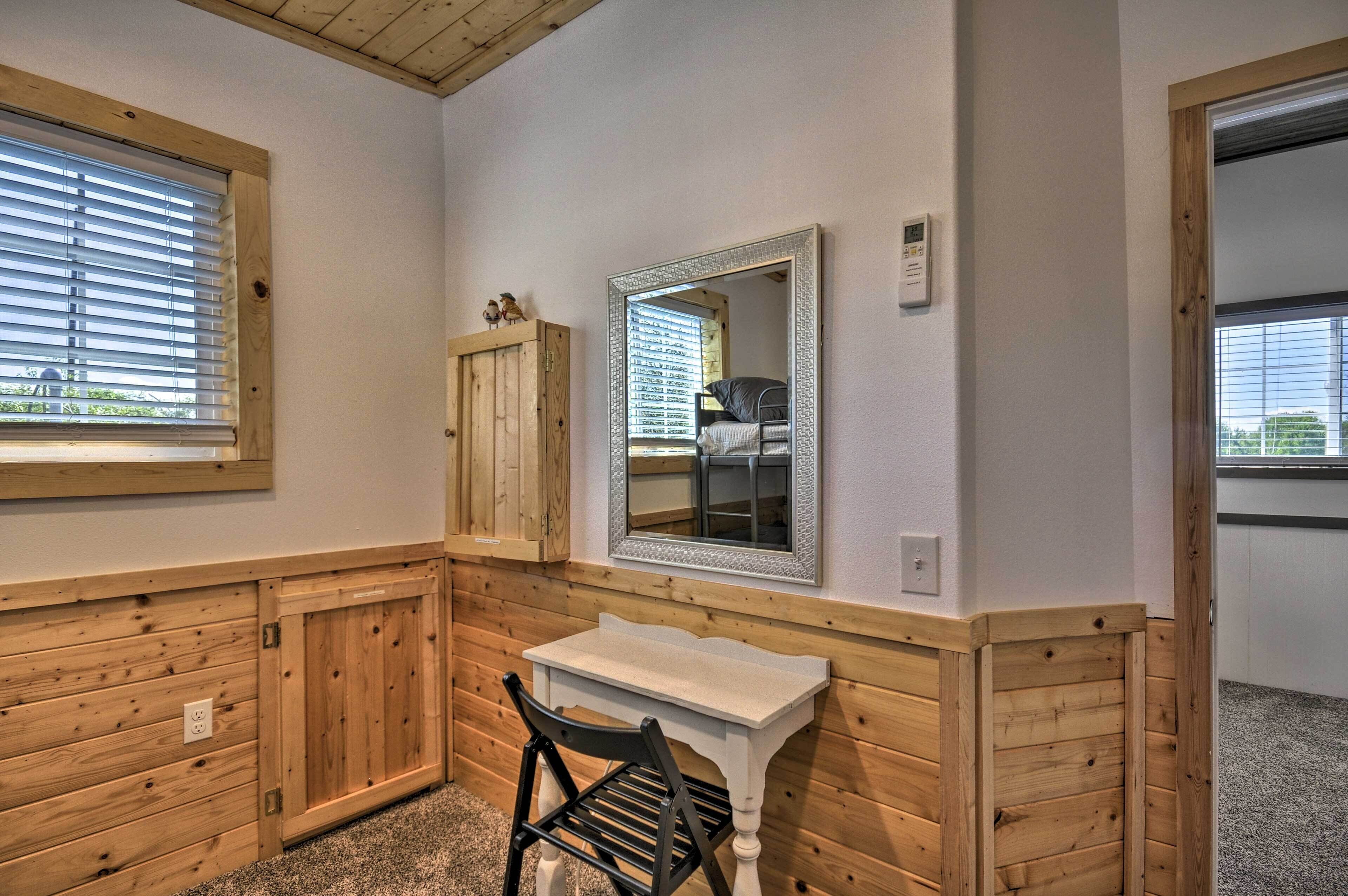 A small bathroom with wooden paneling, a white sink, a mirror, and a window with blinds.