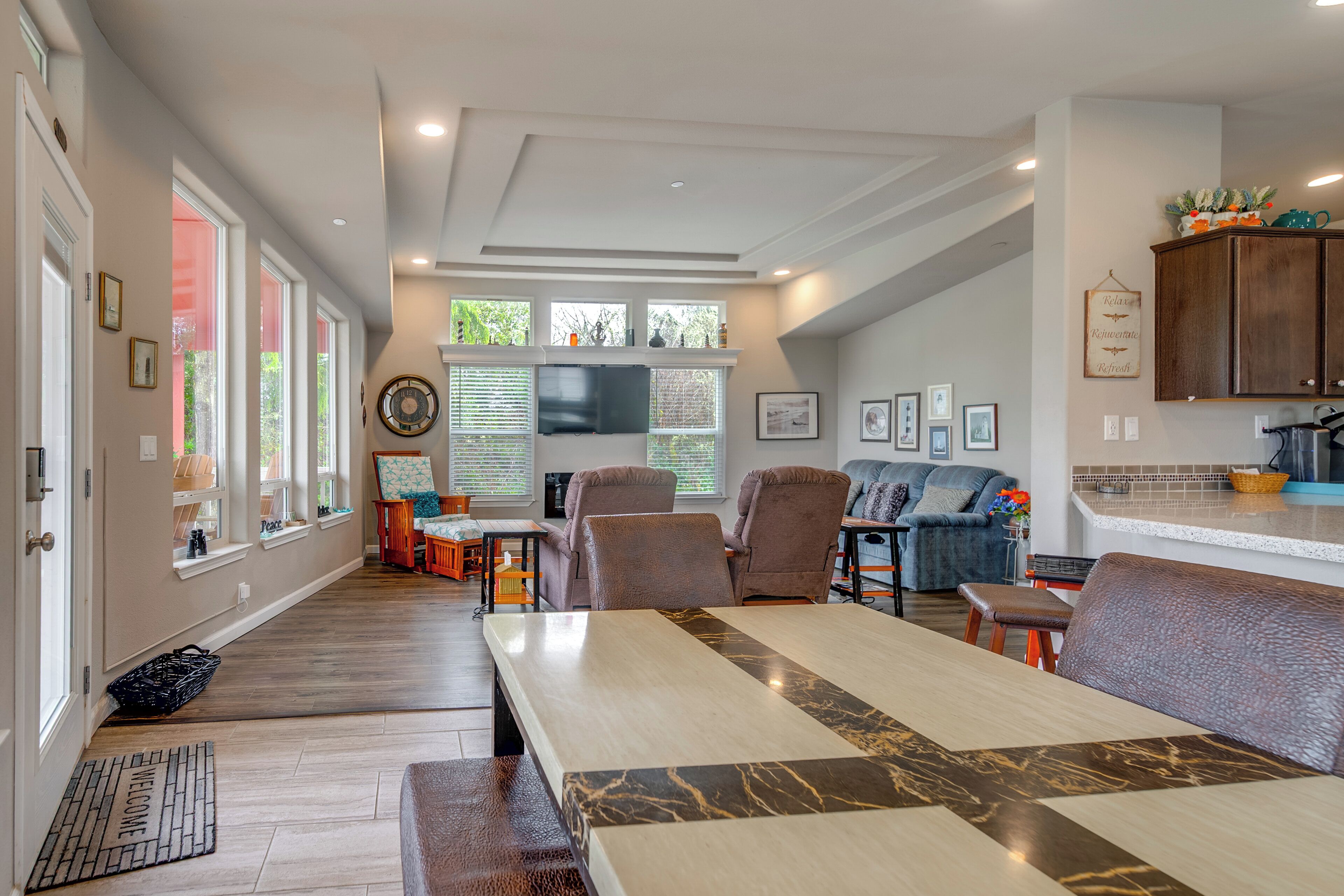 A spacious living room with a large table, comfortable seating, and a kitchen area with cabinets and a countertop.