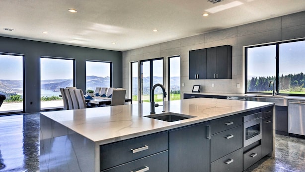 Een moderne keuken met een groot eiland, roestvrijstalen apparatuur en uitzicht op de omgeving.