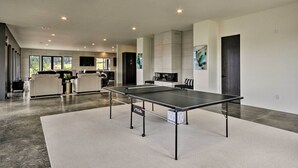 Een ruime kamer met een tafeltennistafel, een kitchenette en een zithoek met banken.