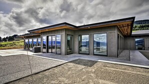 Een modern gebouw met grote glasramen en een plat dak, omgeven door een grindpad en een gazon.