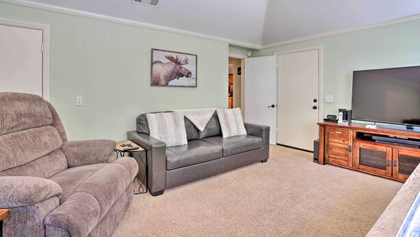 Ein Wohnzimmer mit grauem Sofa, braunem Sessel, Fernseher und einer Holztv-Möbelwand.