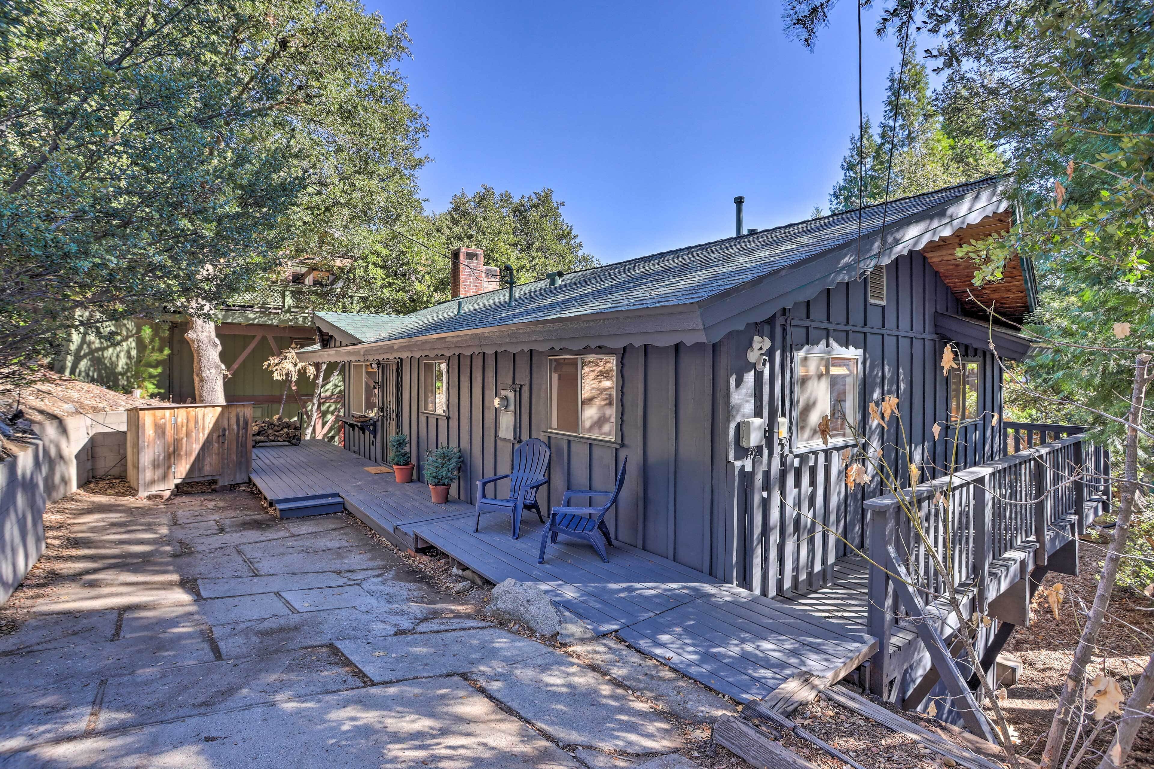 A rustic cabin with a wooden deck, two chairs, and a small porch.