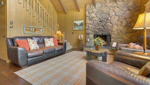 A cozy living room with a stone fireplace, leather sofas, and a wooden ceiling. - Lake Arrowhead Family Home w/ Game Room (Lake Arrowhead)