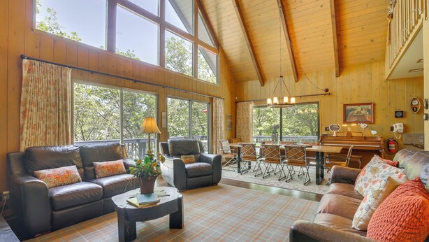 A spacious living room with leather sofas, a coffee table, and a dining area with a piano. - Lake Arrowhead Family Home w/ Game Room (Lake Arrowhead)