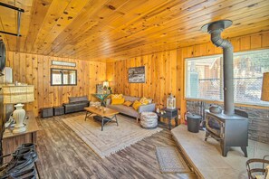 L’intérieur chaleureux d’un chalet, avec un décor en bois, un canapé, une table basse, une cheminée et une fenêtre offrant une belle vue.