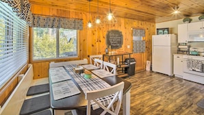 Un interior de madera con una mesa de comedor, sillas, una cocina con electrodomésticos y una pizarra con un mensaje.