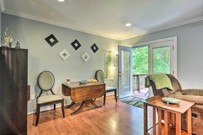 Uma sala de jantar com mesa e cadeiras de madeira, um armário e vista para o exterior através de uma porta de vidro.
