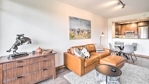 A modern living room with a leather sofa, a wooden cabinet, and a dining area with a table and chairs.