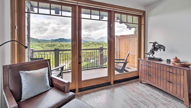 A room with a wooden bench, a cabinet, and a view of a balcony with a railing.