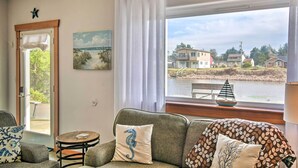 A cozy room with a view of a lake, a sofa with decorative pillows, a small table, and a painting on the wall. - Waterfront Vacation Rental in Ocean Shores (Ocean Shores)