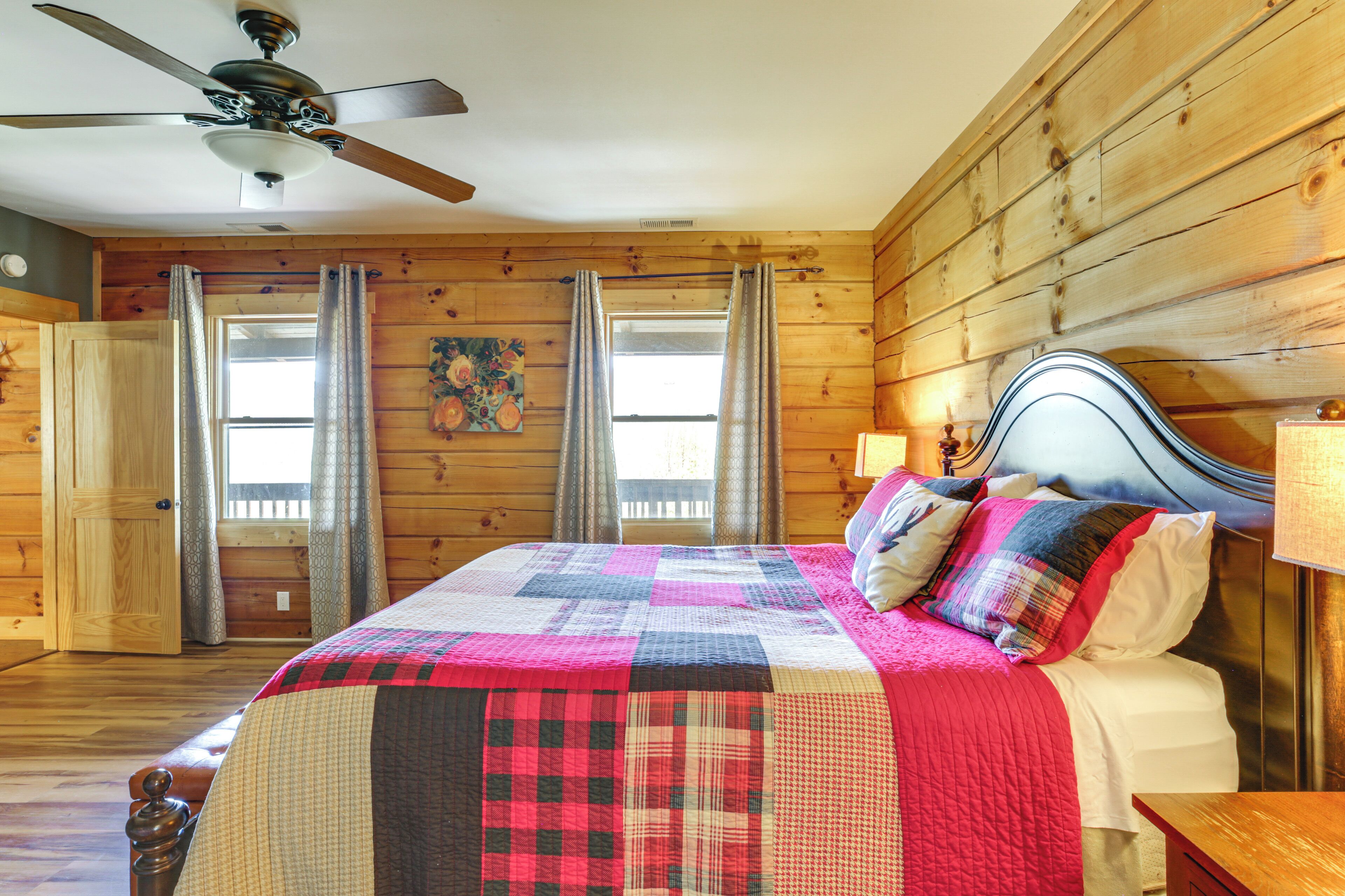 A wooden-paneled bedroom with a bed, curtains, a ceiling fan, and a window.