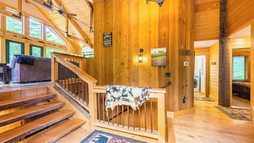 A wooden interior with a staircase, a welcome sign, and a view of the outdoors.