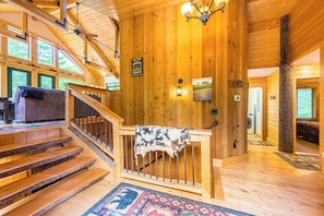 A wooden interior with a staircase, a welcome sign, and a view of the outdoors. - Olympic Natl Park Base: Luxe Port Angeles Cabin (Port Angeles)