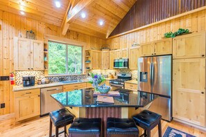 A wooden cabin kitchen with a glass island, stainless steel appliances, and a fire extinguisher. - Olympic Natl Park Base: Luxe Port Angeles Cabin (Port Angeles)