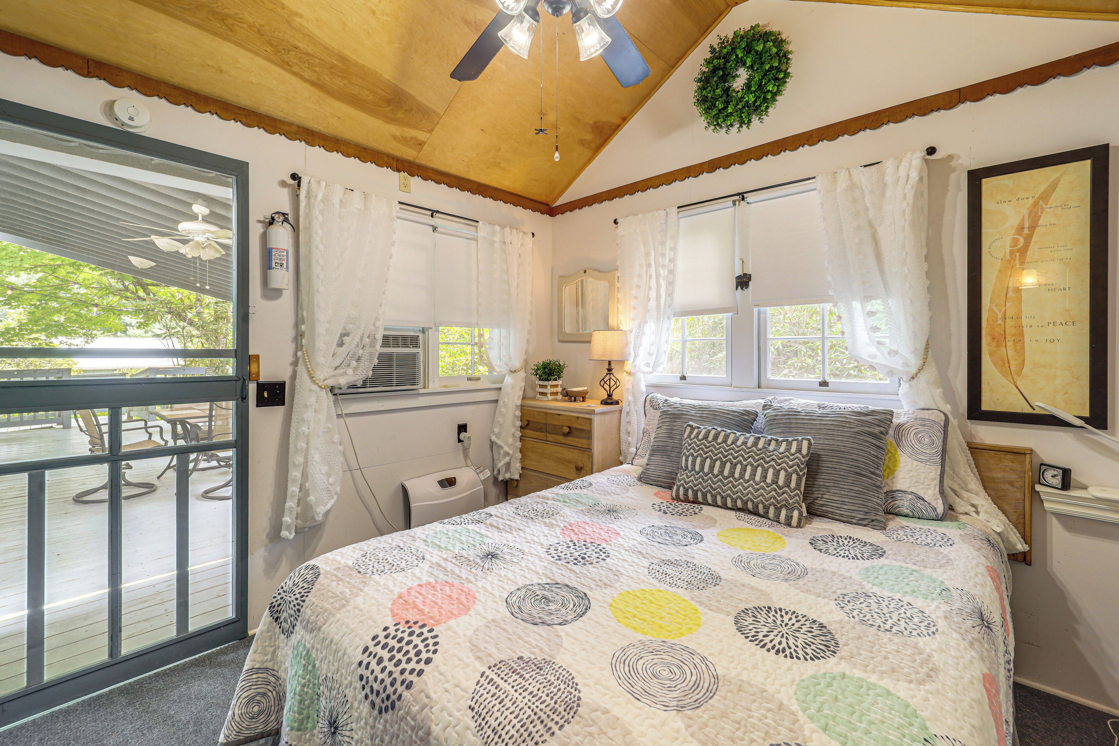 A bedroom with a bed, a window, a door, and a ceiling fan.