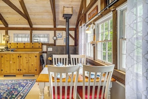 A wooden interior with a dining table, chairs, a kitchen area, and large windows. - 6 Mi to Grandfather Mtn: Lake Cottage w/ Deck (Newland)