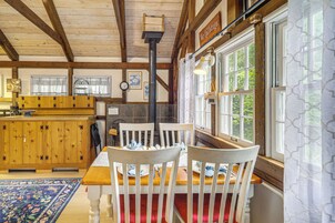 Un interior de madera con una mesa de comedor, sillas, zona de cocina y ventanas amplias.