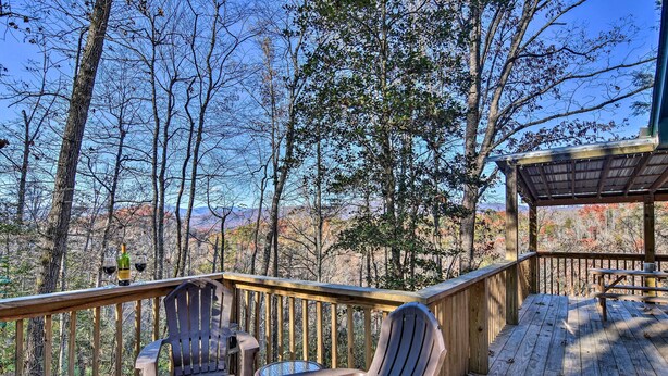 A wooden deck with Adirondack chairs and a table, overlooking a forested area with autumn foliage. - 'nature's Retreat' w/ Hot Tub: 7 Mi to Bryson City (Whittier)