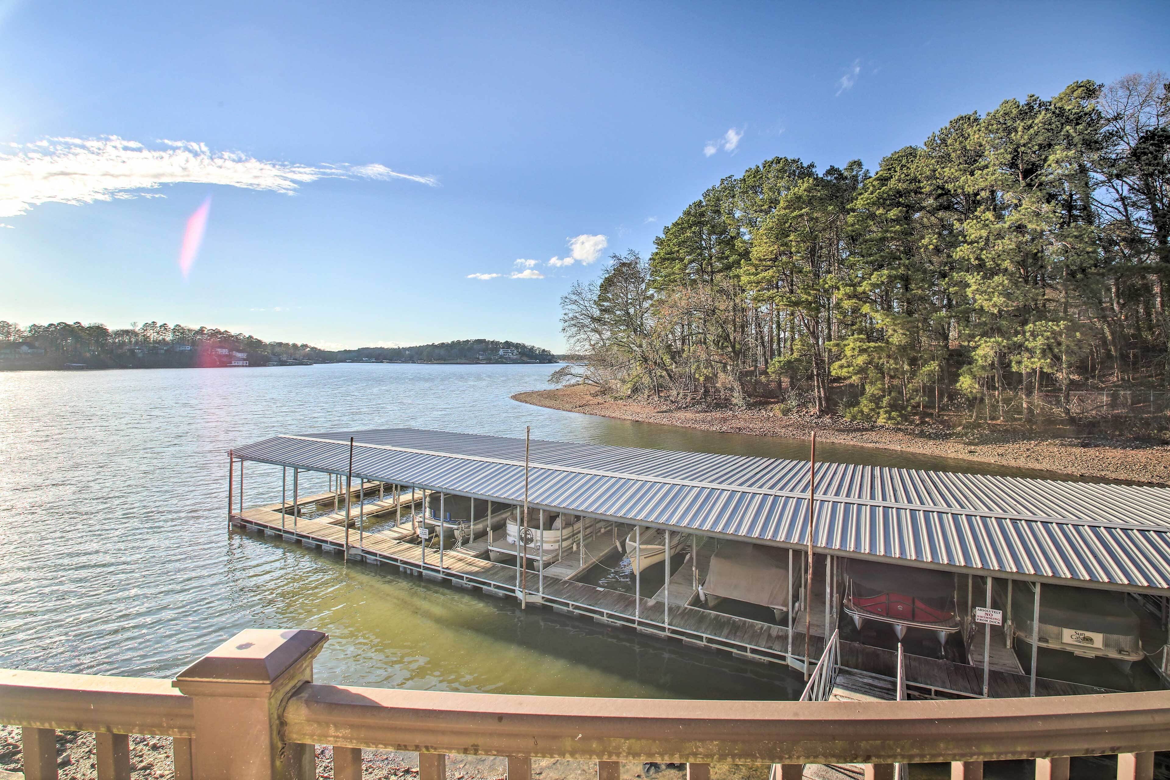 A docked boat with a covered area and a building on a lakeside property.