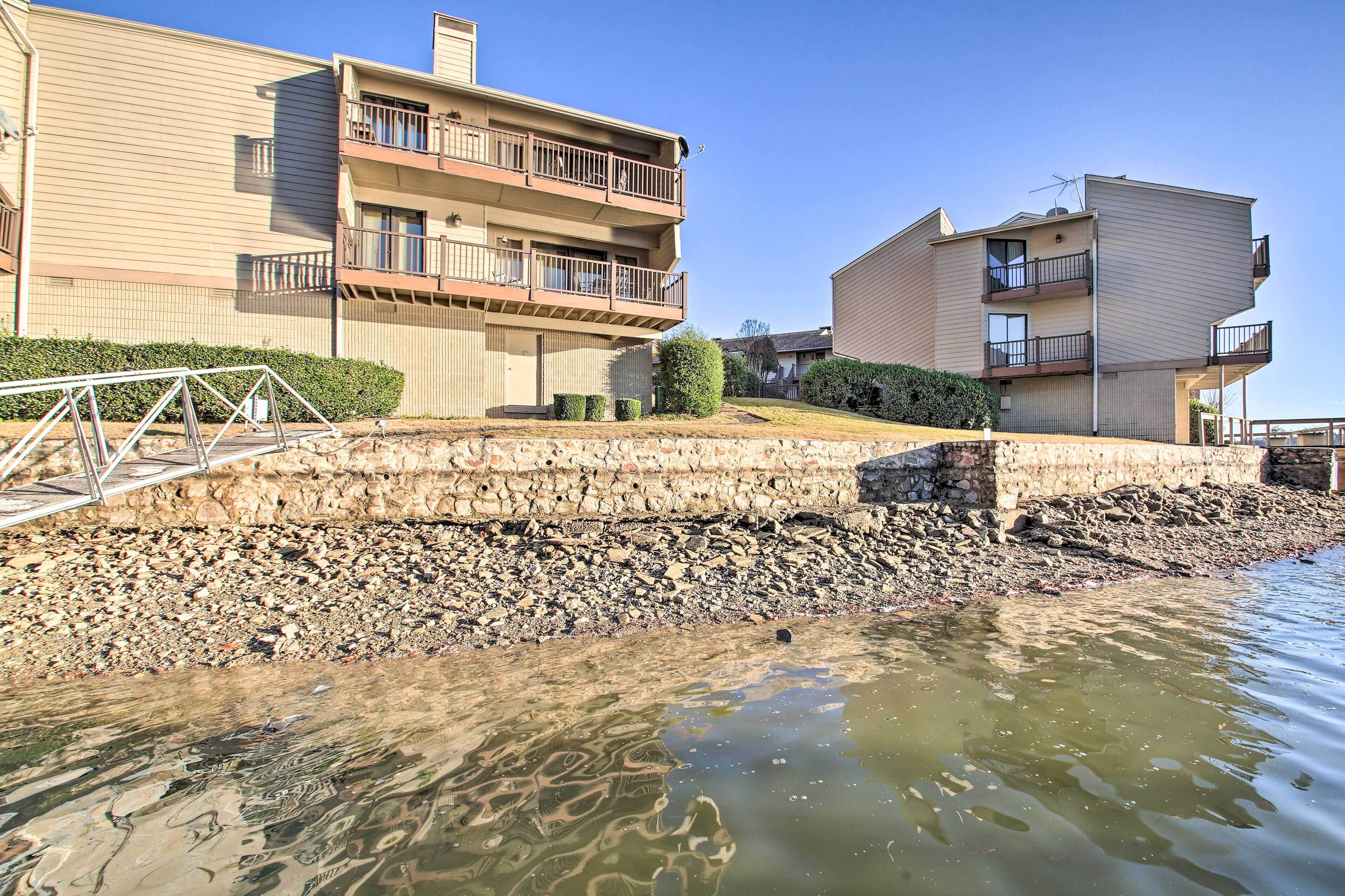 A residential building with multiple balconies, a stone retaining wall, and a clear view of the water body.