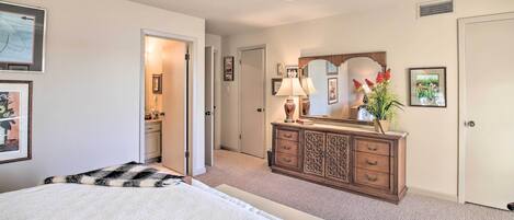 A bedroom with a bed, dresser, mirror, and framed pictures on the walls.