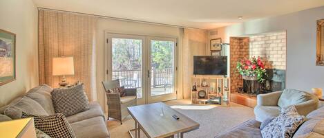 A living room with a sofa, a coffee table, a TV, and a fireplace.