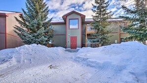 A building with a red door and a small window, surrounded by snow and trees. - Cozy Breckenridge Condo: Free Ski Shuttle Access! (Breckenridge)