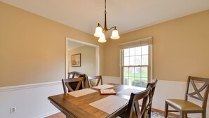A dining room with a wooden table, four chairs, a chandelier, and a window with blinds. - Cozy Home w/ Fenced Yard < 1 Mi Downtown Matthews! (Matthews)