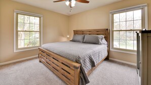 A bedroom with a wooden bed, two windows, a ceiling fan, and a nightstand. - Cozy Home w/ Fenced Yard < 1 Mi Downtown Matthews! (Matthews)