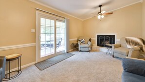 A living room with a fireplace, a ceiling fan, and a large sliding glass door leading to an outdoor patio. - Cozy Home w/ Fenced Yard < 1 Mi Downtown Matthews! (Matthews)